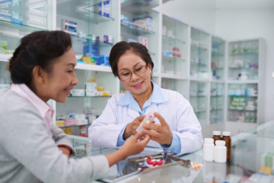 Senior Vietnamese pharmacist and customer discussing medications